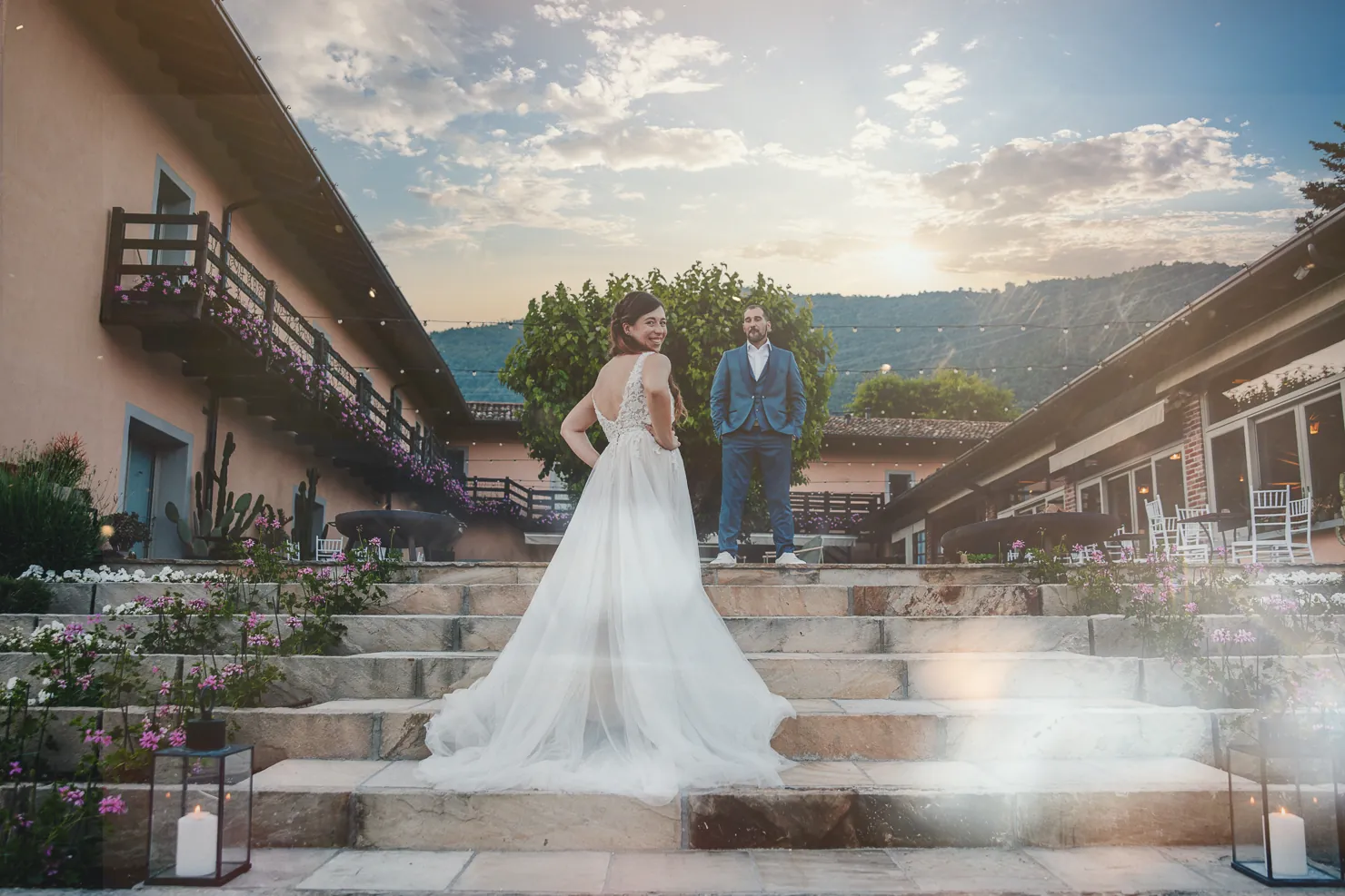 Elisa e Fabio sulla scalinata in pietra tra le due ali de La Corte e il Sogno, con il cielo del tramonto e le colline sullo sfondo